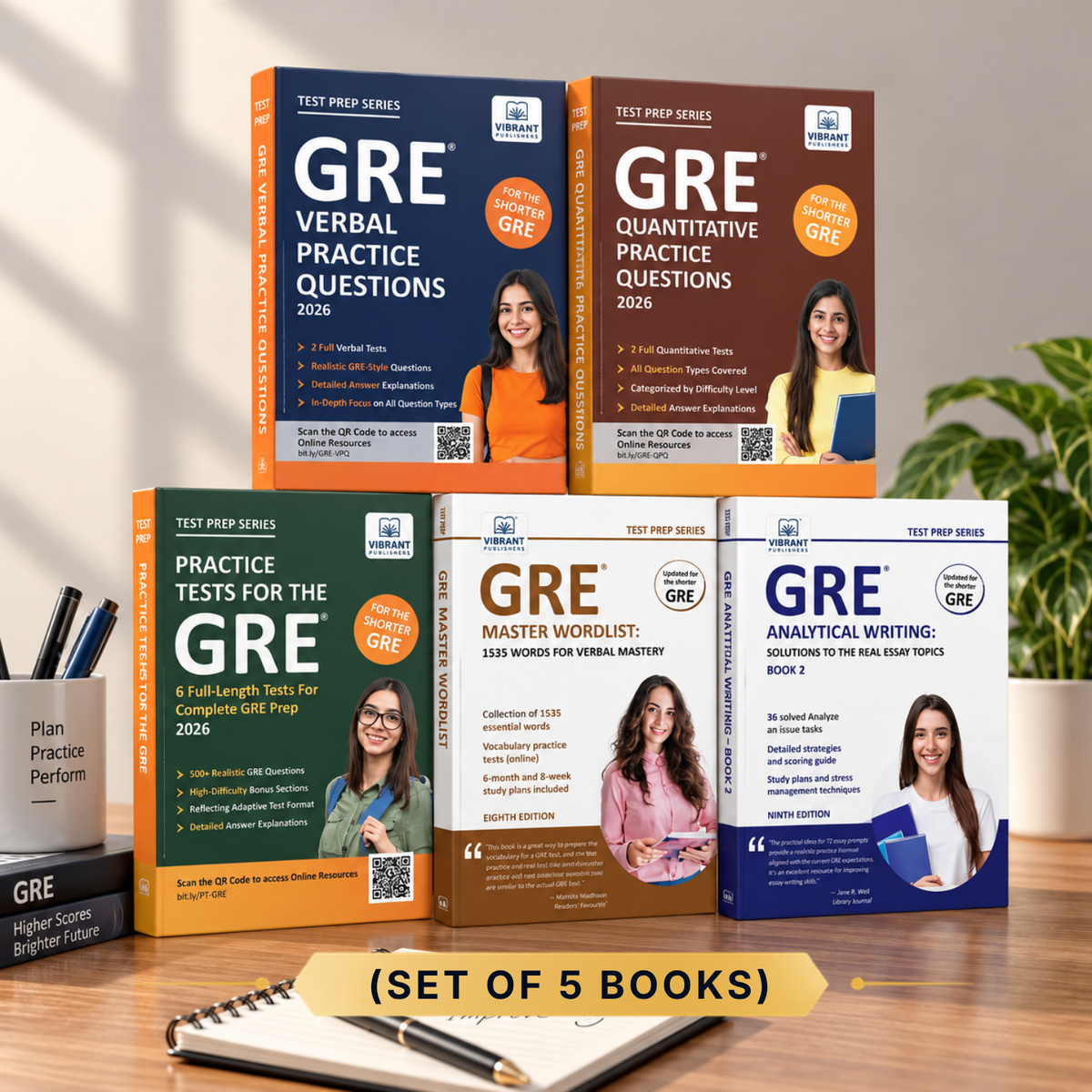 A set of five GRE practice test books arranged on a wooden desk, with a notebook and pens in the foreground and a plant in the background. The books are for the 2026 GRE and include verbal practice, quantitative practice, practice tests, a master workbook, and analytical writing.